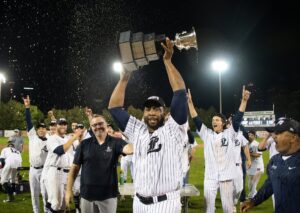Baseball player holding a trophy above his head.