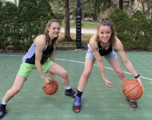 Two girls dribbling basketballs.